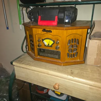 Sale Photo Thumbnail #77: Vintage-style wooden Audio-Technica turntable music center with built-in radio and speakers, sitting on a wooden baker's rack beneath a black tool case.