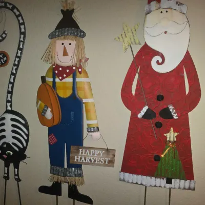 Sale Photo Thumbnail #81: Collection of decorative painted metal yard stakes featuring a scarecrow holding a 'Happy Harvest' sign, a Santa Claus with a star wand, and a black skeleton cat.