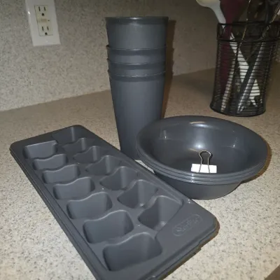 Sale Photo Thumbnail #122: Set of dark gray plastic kitchenware including an ice cube tray, a stack of tumblers, and a stack of small bowls.