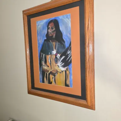 Sale Photo Thumbnail #32: Framed original portrait painting depicting a Native American figure holding an eagle feather, set within a double mat and a oak wood frame.