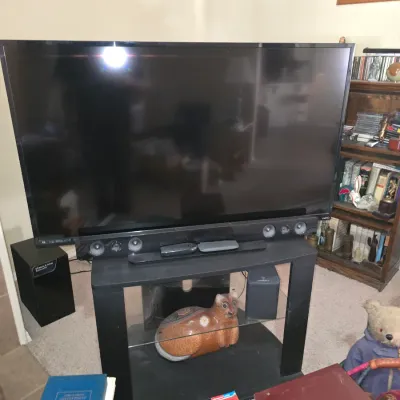 Sale Photo Thumbnail #40: Vizio flat-screen television resting on a black two-shelf media stand with an attached soundbar and accompanying subwoofer.