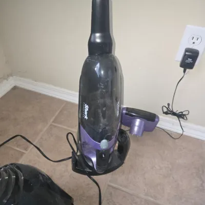 Sale Photo Thumbnail #69: Shark cordless handheld vacuum cleaner with purple accents, charging base, and motorized brush attachment.