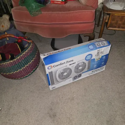 Sale Photo Thumbnail #39: Comfort Zone twin window fan in original box, sitting on carpet in front of a pink upholstered armchair.