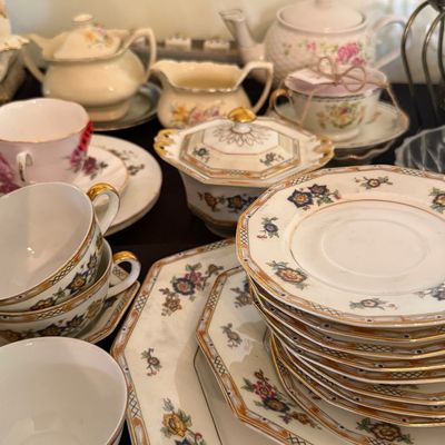 Sale Photo Thumbnail #30: Collection of vintage porcelain teacups, saucers, platters, and teapots featuring gold trim and floral motifs.