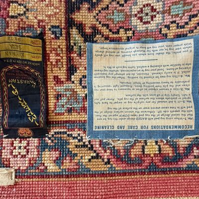 Sale Photo Thumbnail #67: Underside detail of a Karastan 9x12 Kirman pattern area rug, featuring original maker's labels and care instructions tag.