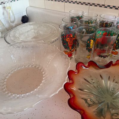 Sale Photo Thumbnail #24: Collection of glassware including a large frosted clear bowl, an amber glass bowl with a red ruffled rim, etched serving plates, and a set of Twelve Days of Christmas drinking glasses.