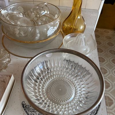Sale Photo Thumbnail #23: Collection of vintage glassware, including a silver-rimmed cut glass bowl, an amber swings vase, a glass citrus juicer, and a punch bowl set with frosted floral details.
