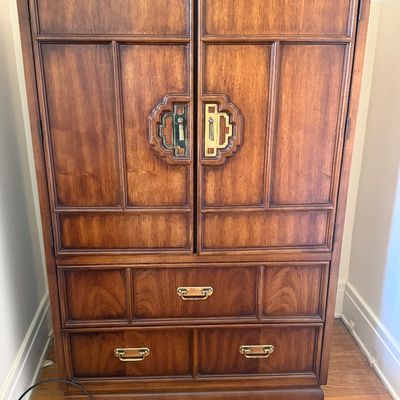 Sale Photo Thumbnail #4: Mid-century Asian-inspired wooden armoire cabinet featuring ornate brass hardware and lower storage drawers.