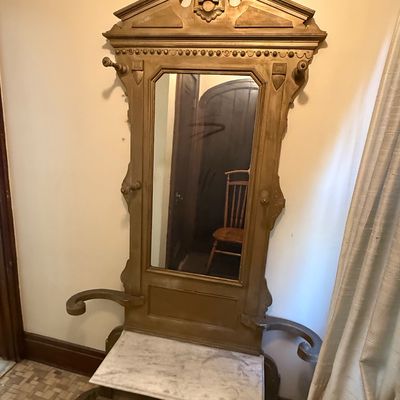 Sale Photo Thumbnail #41: Antique Victorian-style hall tree featuring an ornate carved pediment, center mirror, coat hooks, and a white marble-top lower console.