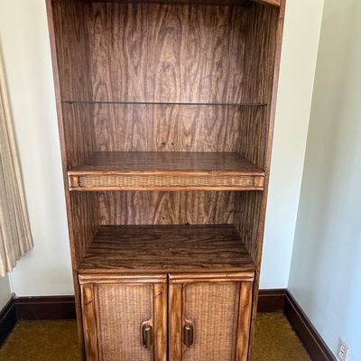Sale Photo Thumbnail #47: Vintage tropical-style wood bookshelf unit featuring woven wicker paneling, open shelving with one glass shelf, and a lower two-door storage cabinet.
