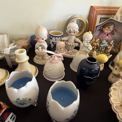 Sale Photo Thumbnail #56: Collection of decorative porcelain figurines, including Precious Moments statues, ceramic bells, candlestick holders, and small vases.