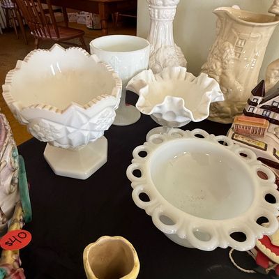 Sale Photo Thumbnail #58: Collection of vintage white milk glass items including a lace-edge bowl, ruffled footed dish, and pressed glass urn, shown alongside decorative ceramics.