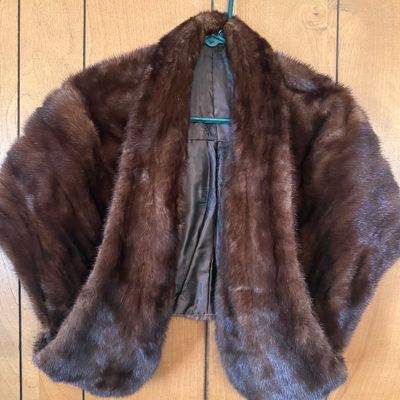 Sale Photo Thumbnail #65: Vintage dark brown mink fur stole wrap with a silky inner lining, displayed on a hanger against a wood panel wall.