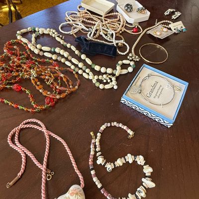 Sale Photo Thumbnail #45: Assortment of vintage costume jewelry, featuring beaded necklaces, faux pearl strands, clip-on earrings, and a boxed "Grandma" stainless steel charm bangle.