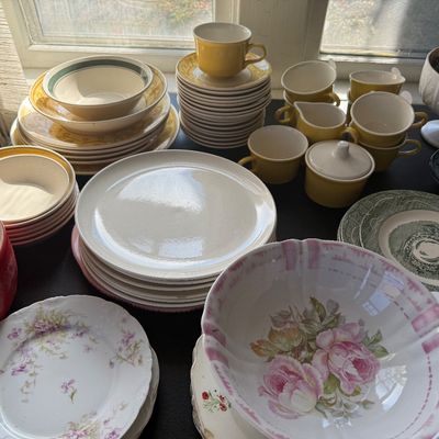 Sale Photo Thumbnail #20: Large assortment of vintage dishware and china, featuring mid-century yellow tea sets, floral-patterned plates, and Transferware pieces.