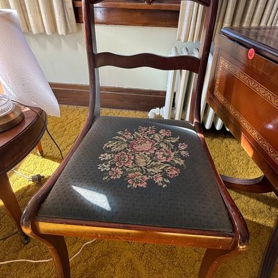 Sale Photo Thumbnail #52: Vintage carved wooden dining chair featuring a carved floral top rail and a dark fabric upholstered seat with floral embroidery.