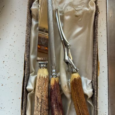 Sale Photo Thumbnail #16: Vintage three-piece Sheffield stainless steel carving set with stag horn handles, including a carving knife, sharpening steel, and meat fork, presented in its original satin-lined box.