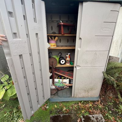 Rubbermaid outdoor resin storage shed containing various garden tools and supplies.