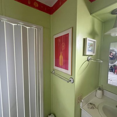 Framed floral art print featuring a yellow vase on a pink background, alongside a small framed bathtub illustration in a light green...