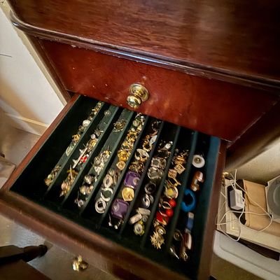 Open felt-lined drawer filled with various vintage costume jewelry pieces, including clip-on earrings, brooches, and rings.