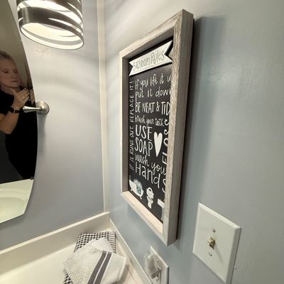 Framed 'Bathroom Rules' chalkboard-style wall art in a rustic whitewashed wood frame.