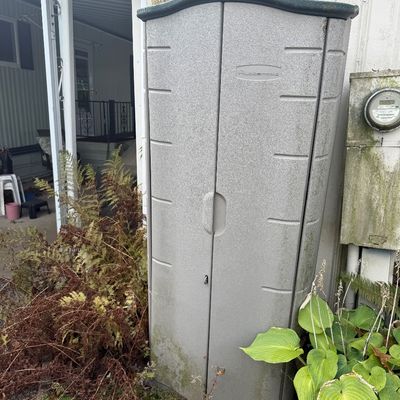 Tall, outdoor Rubbermaid resin storage cabinet with double doors, showing weathering from outdoor use.