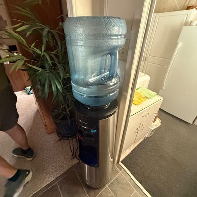 Glacier Bay top-loading water dispenser with stainless steel finish and attached water jug.