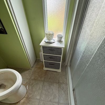 Small white bathroom organizer unit with three grey fabric drawers, topped with decorative white ceramic items.