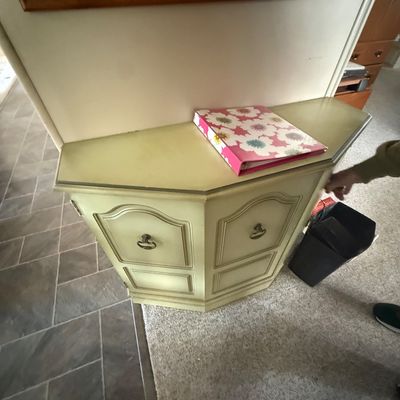 Vintage French Provincial style pale yellow corner accent cabinet featuring molded door panels and brass bail handles.