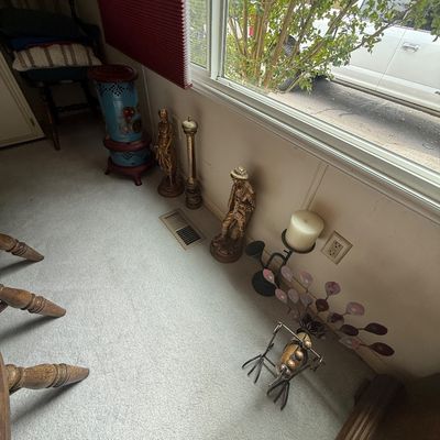 A collection of floor decor items, including brass figurines, a metal peacock sculpture, a tall wooden pepper mill, a candle holder, and...