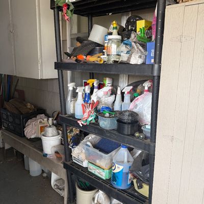 Black plastic five-tier shelving unit holding various household, garden, and garage cleaning supplies and containers.