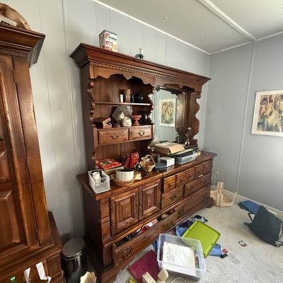 Large vintage dark wood hutch and dresser combination featuring a mirrored back, open shelving, and ornate paneled drawers.