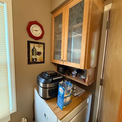 Kitchen nook featuring light oak wall cabinet with etched glass doors, a PowerXL multi-cooker sitting atop a small counter unit, an...