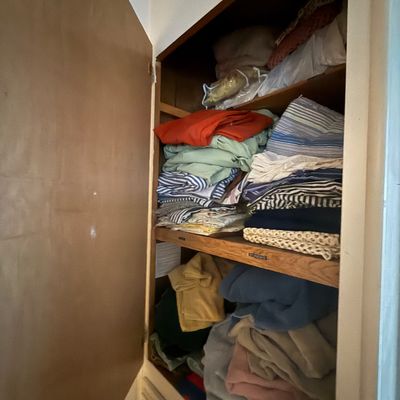 Linen closet filled with stacked bed sheets, blankets, towels, and various household textiles.