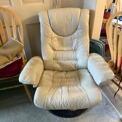 Off-white leather swivel recliner armchair featuring a high back and padded armrests.
