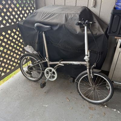Silver-tone Monti folding bicycle with front and rear fenders and a rear storage rack.