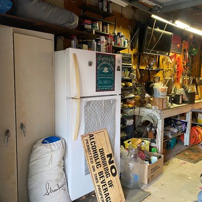Sale Photo Thumbnail #105: White top-freezer refrigerator in a workshop, alongside a printed 'No Drinking of Alcoholic Beverages' sign, a large glass carboy, and a Slumberjack bag.