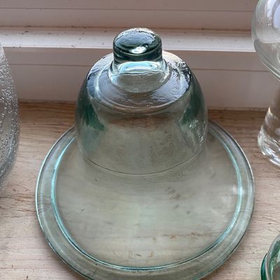 Sale Photo Thumbnail #92: Vintage heavy light-green glass jar lid sitting upside down on a wooden surface.