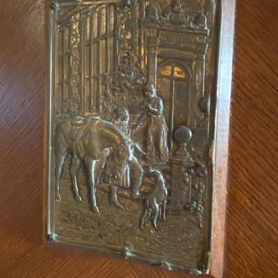 Sale Photo Thumbnail #71: Vintage repoussé metal relief plaque mounted on a wooden backer, depicting a equestrian scene with figures and a dog.