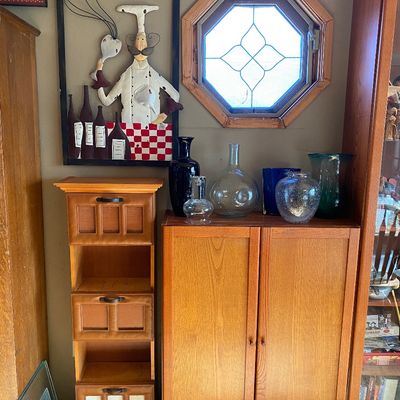 Sale Photo Thumbnail #185: Mid-century style oak cabinets displayed with an assortment of decorative glass vases, clear bottles, and a novelty chef wall hang.