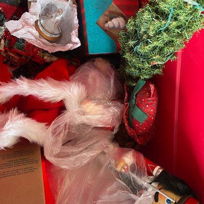 Sale Photo Thumbnail #120: Red storage bin filled with assorted Christmas decorations, including a wooden nutcracker, mini pre-lit tree, glass snow globe, and holiday textiles.