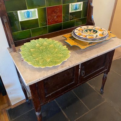 Sale Photo Thumbnail #47: Antique marble-top washstand with green tiled splashback backboard, featuring a leaf-patterned server and hand-painted ceramic platters.