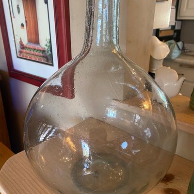 Sale Photo Thumbnail #99: Large clear glass demijohn bottle with a bulbous body and narrow neck, displaying visible seed bubbles throughout the glass.