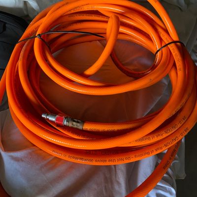 Sale Photo Thumbnail #140: Coiled bright orange air compressor hose with quick-connect fitting, secured with zip ties.