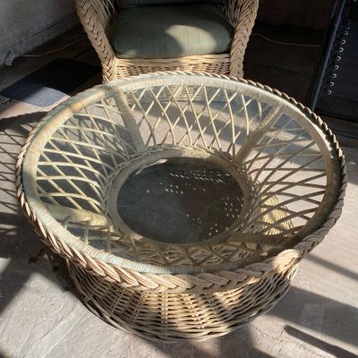 Sale Photo Thumbnail #21: Round wicker coffee table with a insert glass top and lattice-pattern base, paired with a matching armchair with green cushions.
