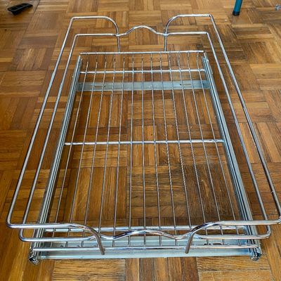 Sale Photo Thumbnail #77: Chrome wire pull-out cabinet organizer basket with sliding hardware, resting on a parquet floor.