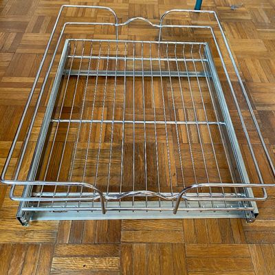 Sale Photo Thumbnail #78: Chrome wire pull-out cabinet shelf organiser with integrated sliding tracks, resting on a parquet floor.
