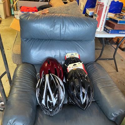 Sale Photo Thumbnail #113: Blue leather overstuffed recliner filled with a collection of four bicycle helmets, including Schwinn brand models.