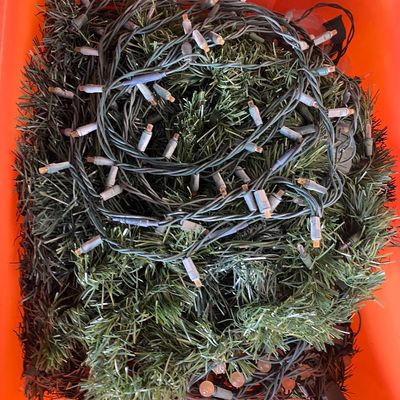 Sale Photo Thumbnail #122: An orange storage tub filled with tangled strands of string lights and artificial green holiday garland.