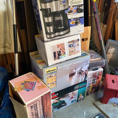Sale Photo Thumbnail #114: Stack of boxed household items including a Hamilton Beach 2-Way Brewer coffee maker, Wagner PaintREADY paint sprayer system, and a Bissell Little Green Machine deep cleaner.